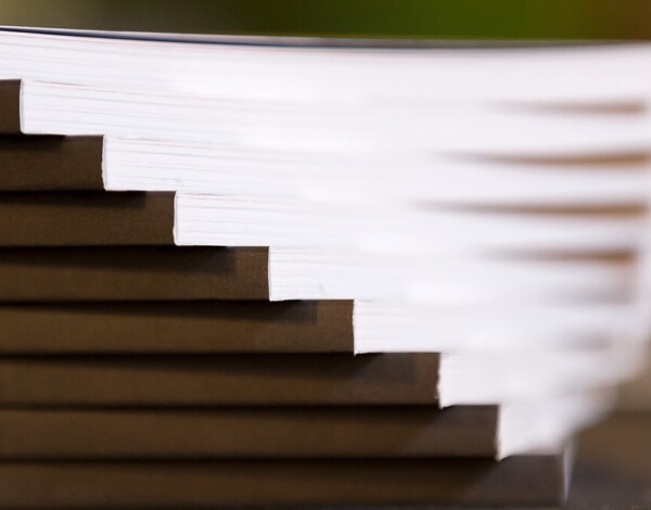 Close-up of a stack of books with visible edges, set on a dark surface.