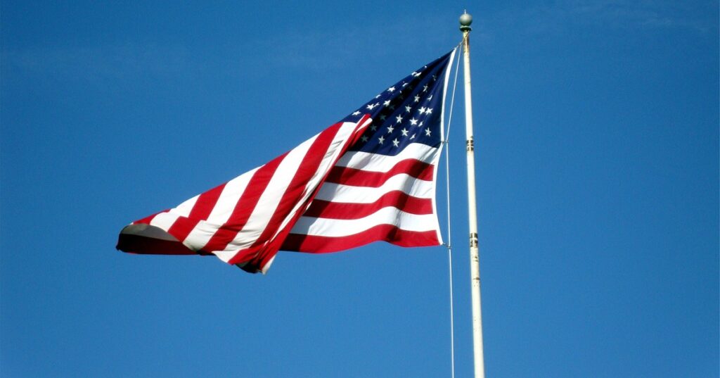US flag flying against a clear blue sky.