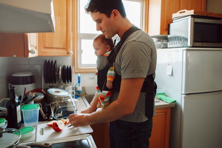 Man cooking with baby in sling