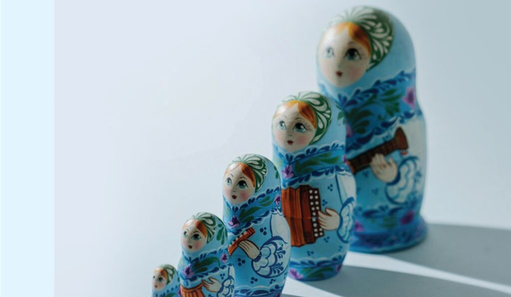 A set of four blue matryoshka dolls with floral patterns arranged by size.