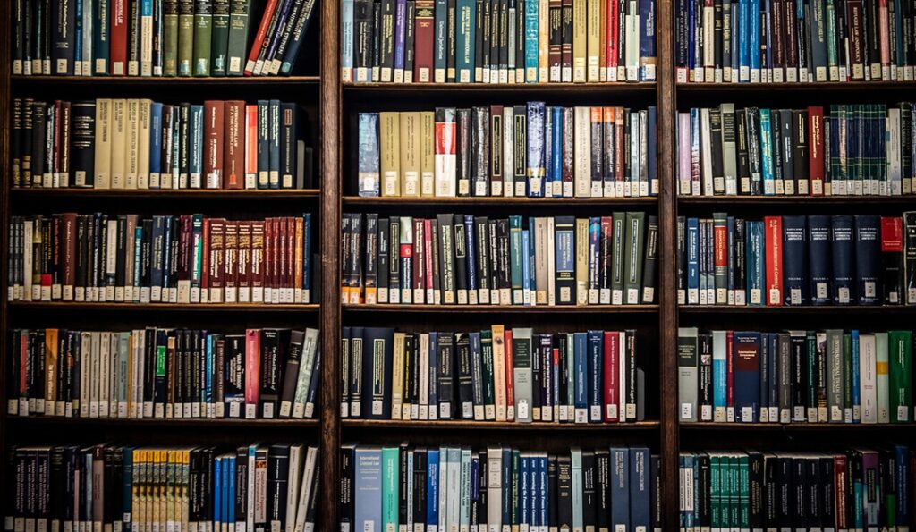 Bookshelves filled with various books in UCL's Main Library, showing colourful spines with labels.