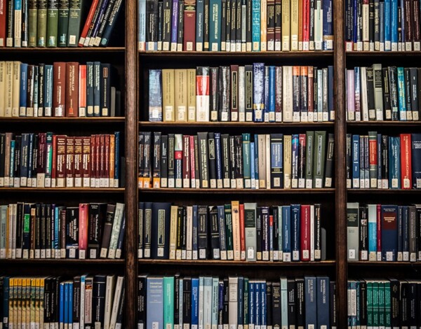 Bookshelves filled with various books in UCL's Main Library, showing colourful spines with labels.