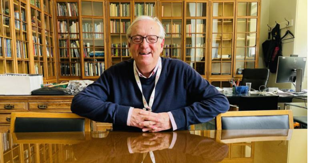 Paul Ayris, sat at his desk, in his office at UCL, smiling.