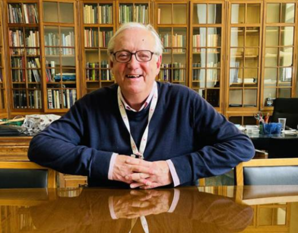 Paul Ayris, sat at his desk, in his office at UCL, smiling.