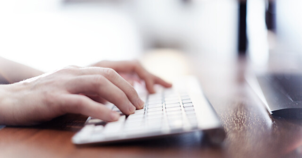Hands typing on a white keyboard
