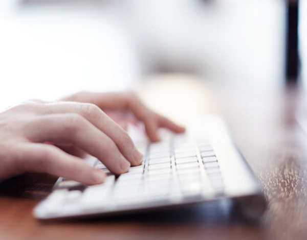 Hands typing on a white keyboard